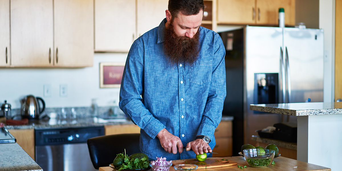 bearded man cutting ingredients for guacamole